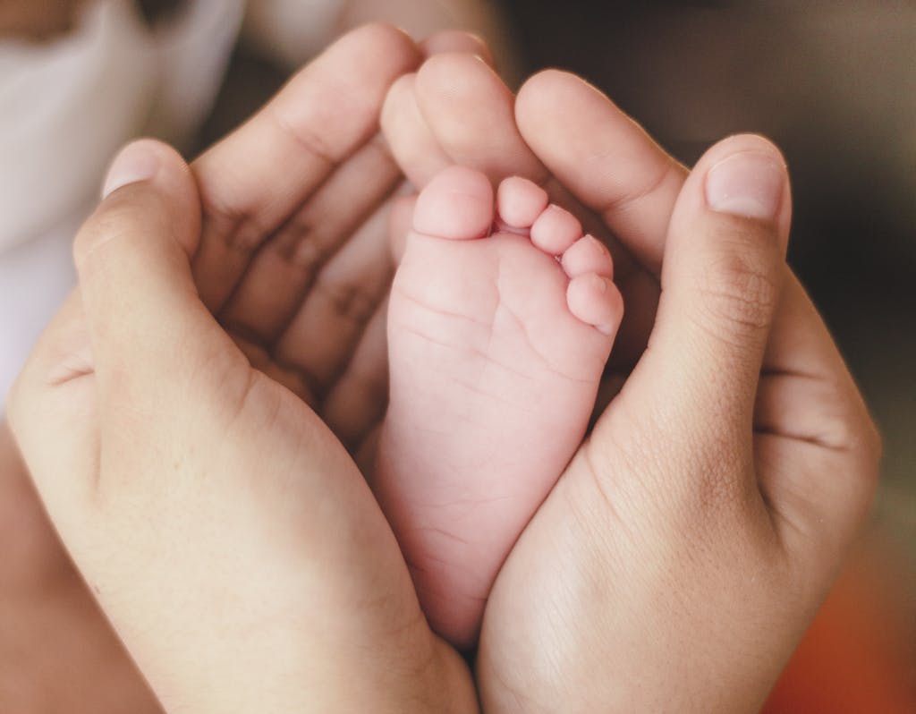 A tender moment capturing a newborn foot in warm adult hands, symbolizing love and care.